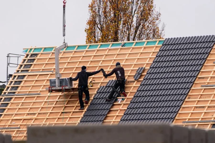 Dachdecker decken ein Dach mit Tonziegeln ein