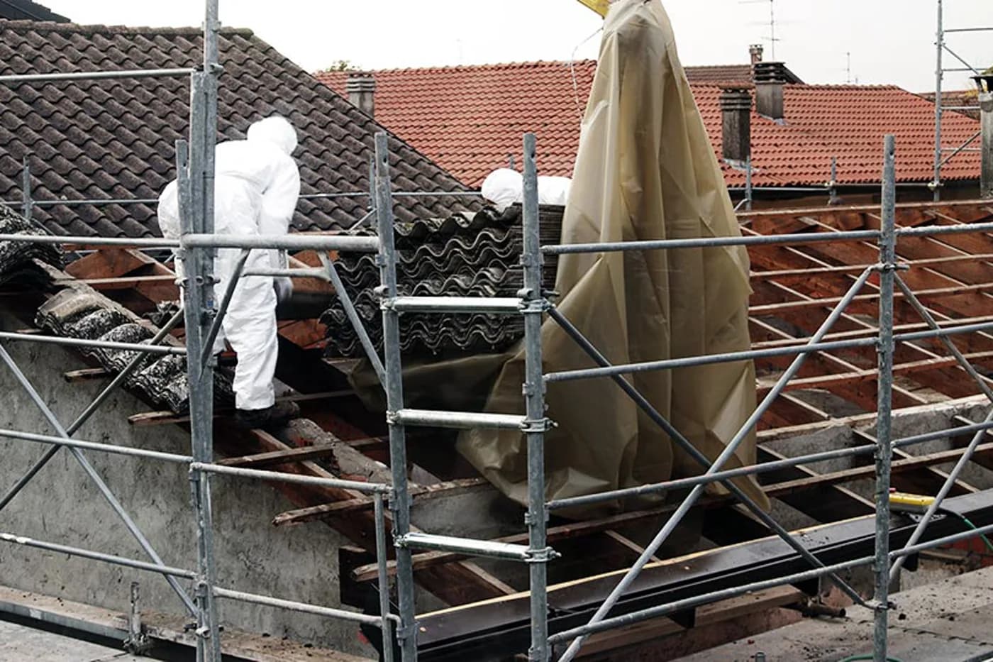 Fachkräfte in Schutzanzügen tragen asbesthaltige Dachplatten ab