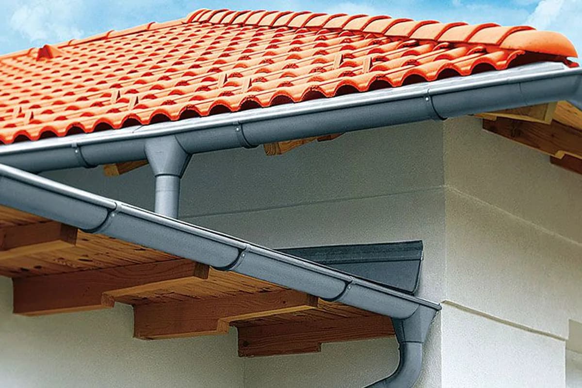 Dachrinne und Fallrohr am Dachrand eines Wohnhauses