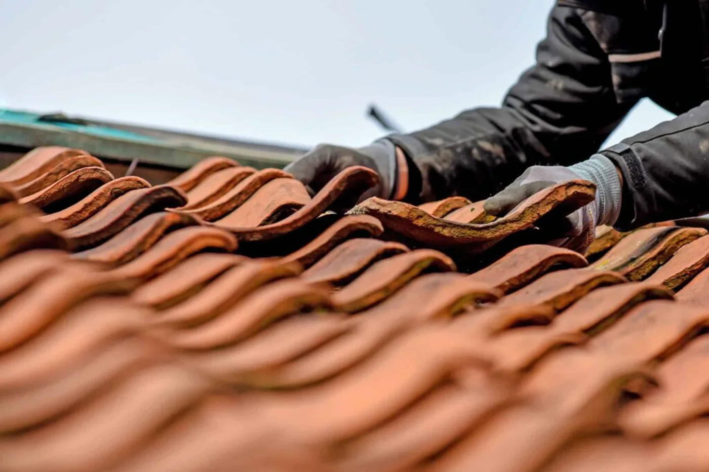 Dachdecker tauscht von Hand einen Dachziegel aus